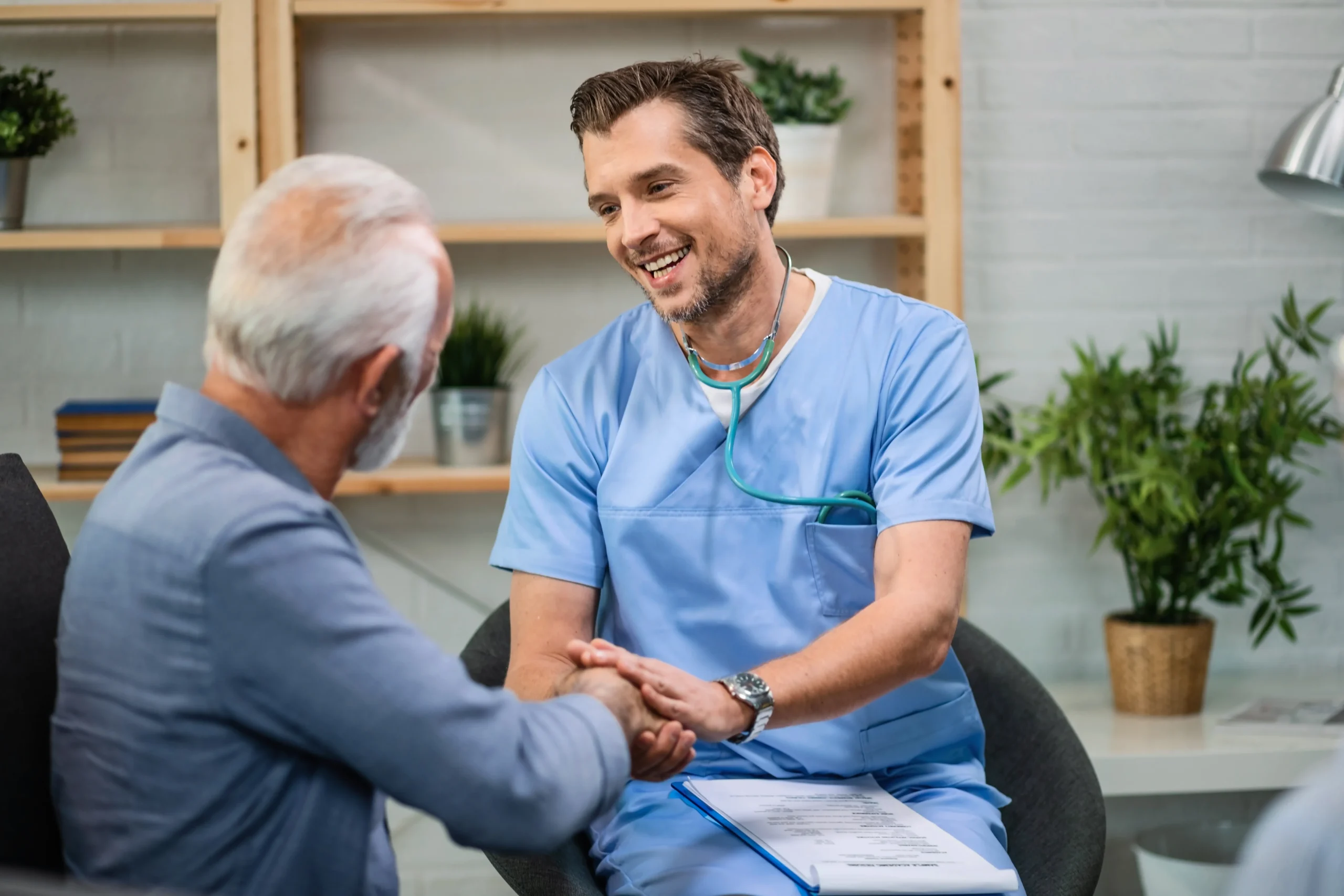 happy-general-practitioner-talking-senior-man-while-shaking-hands-with-him-during-home-visit